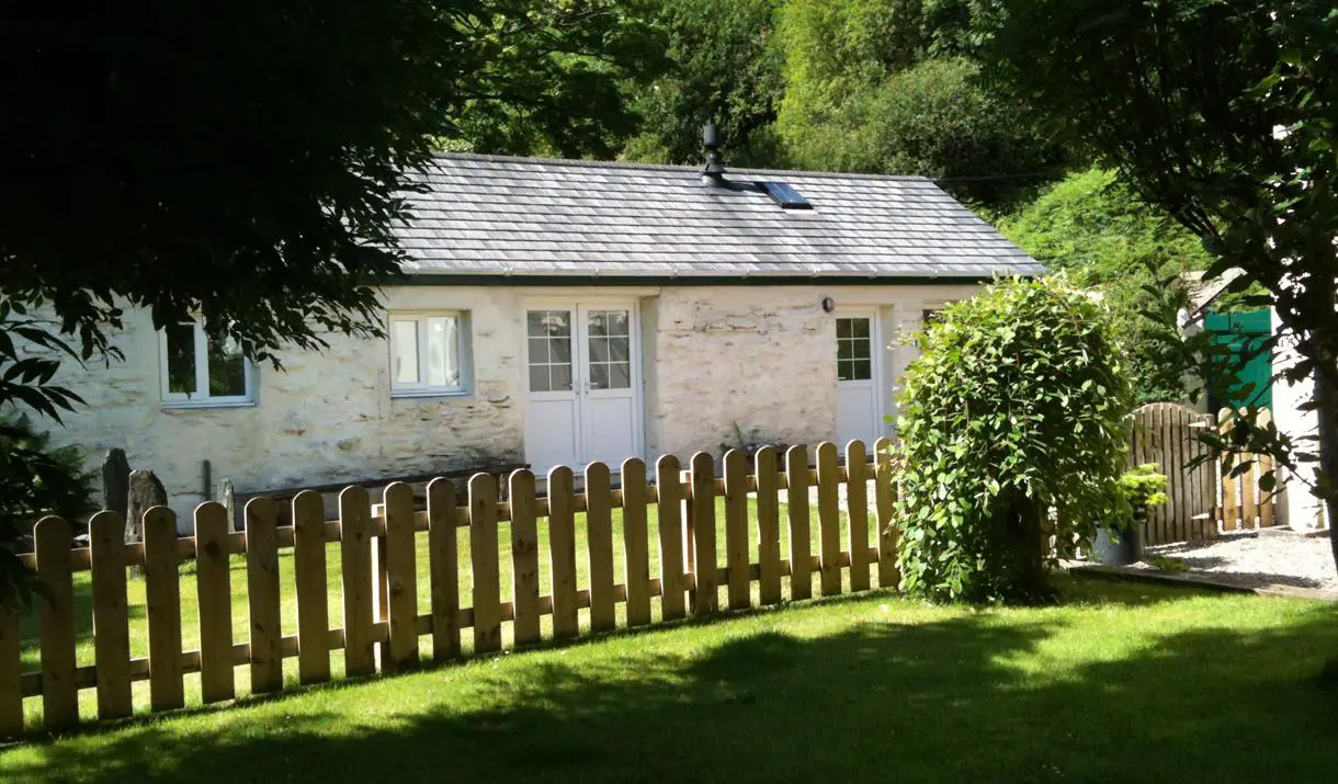 Cottage exterior surrounded by summer greenery